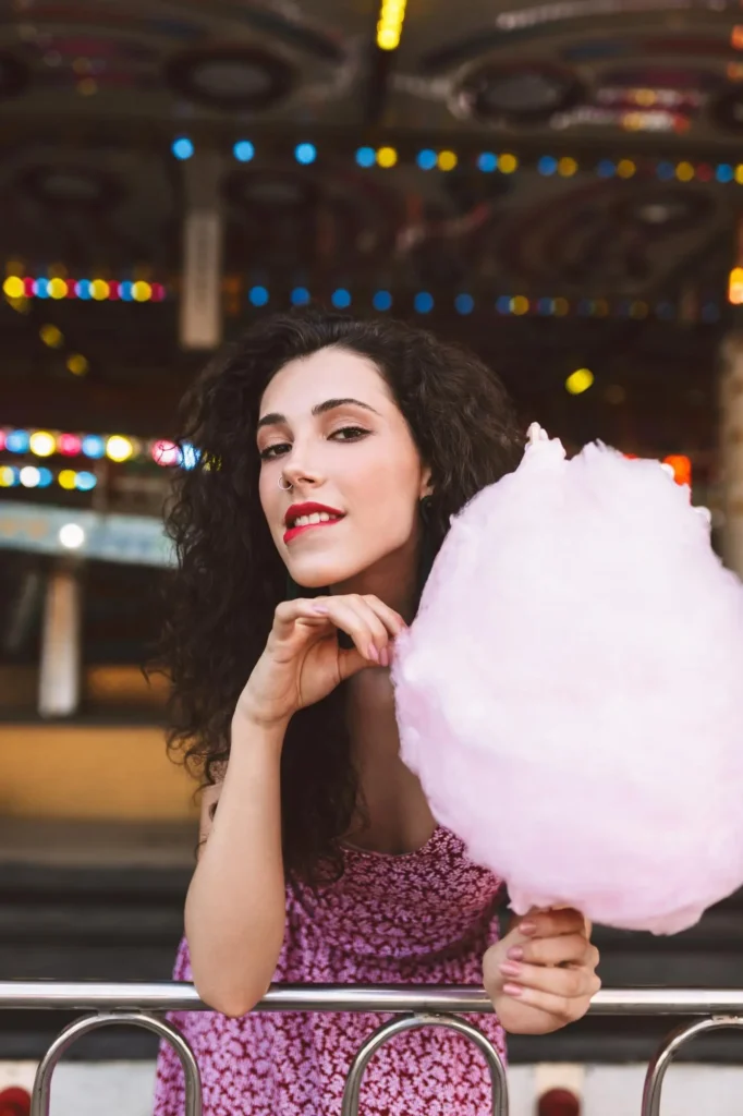 Woman smiling while holding pink cotton candy at a vending machine